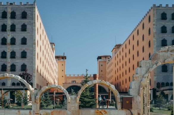 arquitetura-hotel-suhan-cappadocia-turquia Pátio central entre prédios simétricos de cor ocre sob céu azul.