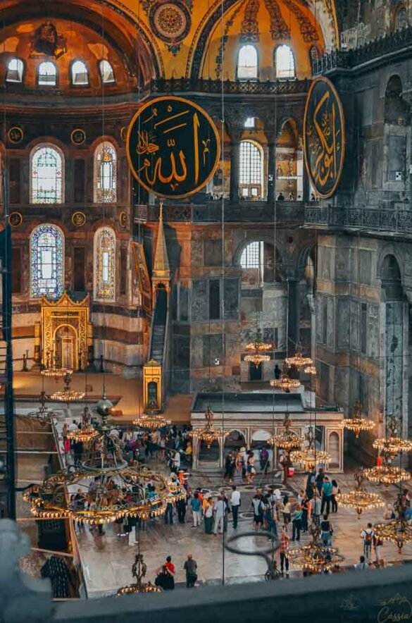 Vista interna da Hagia Sophia com medalhões de caligrafia árabe e lustres circulares.