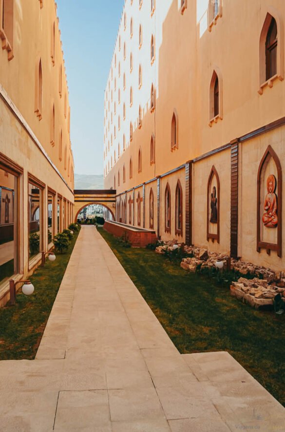 detalhes-esculturas-parede-hotel-capadocia Corredor externo com jardim e nichos na parede contendo relevos decorativos.