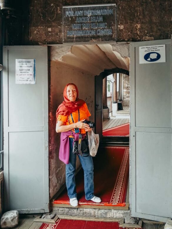 Mulher na entrada do Centro de Informação Islâmica na Mesquita Azul, com placas informativas.