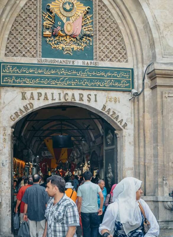 Fachada de pedra do Portão Nuruosmaniye no Grand Bazaar com brasão otomano e caligrafia árabe.