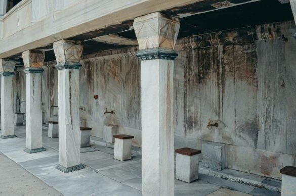 Fileira de fontes de mármore com bancos de pedra para o ritual de purificação em uma mesquita.