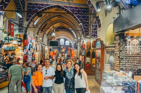 Cinco pessoas sorrindo nos corredores internos do Grand Bazaar sob tetos arqueados pintados.
