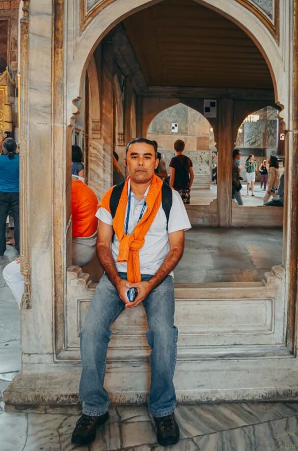 Homem sentado em detalhe de mármore sob arcos bizantinos no interior da Hagia Sophia.