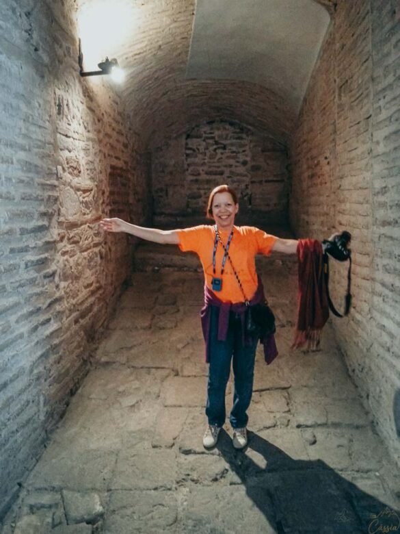 Mulher sorridente de camiseta laranja em um corredor antigo de pedras na Hagia Sophia.