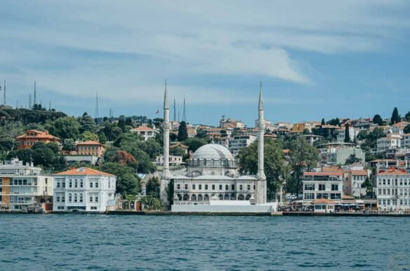 Mesquita clássica com dois minaretes situada na margem do mar sob céu azul em Istambul.