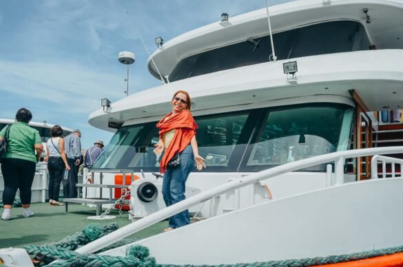 Mulher sorridente com echarpe laranja no convés de um barco branco em Istambul.