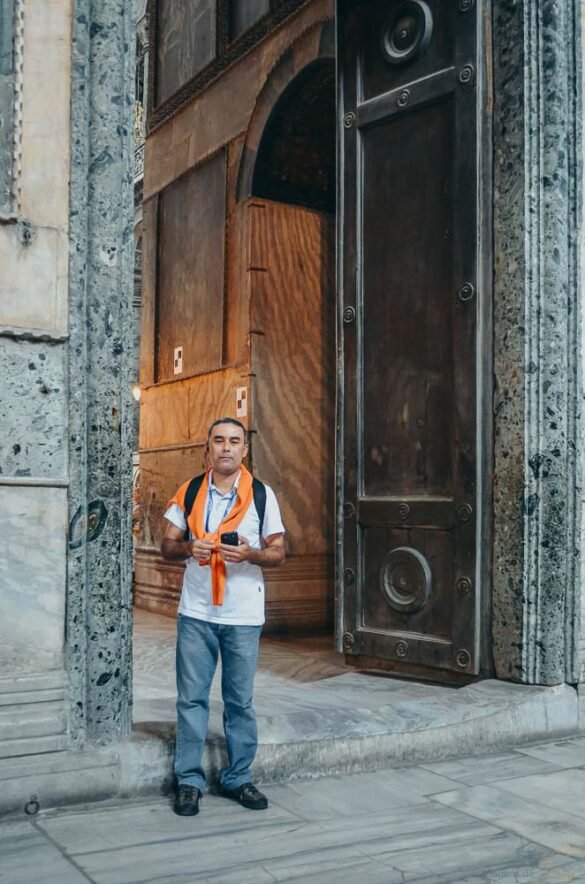 Homem em frente a um enorme portão de madeira e bronze na entrada da Hagia Sophia.