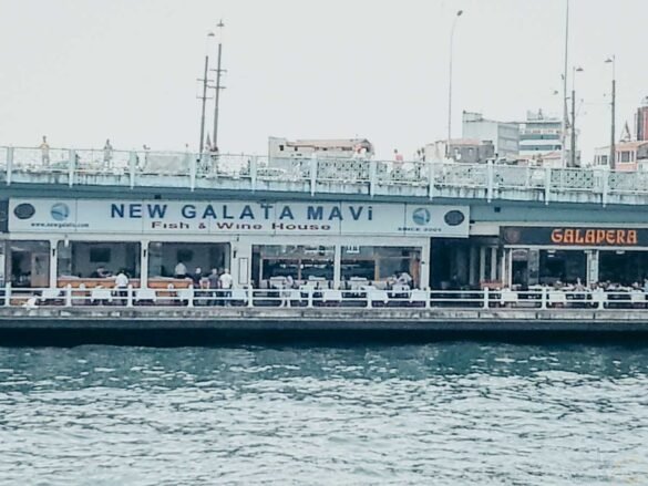 Vista externa dos restaurantes New Galata Mavi e Galapera sob a estrutura da Ponte Gálata.