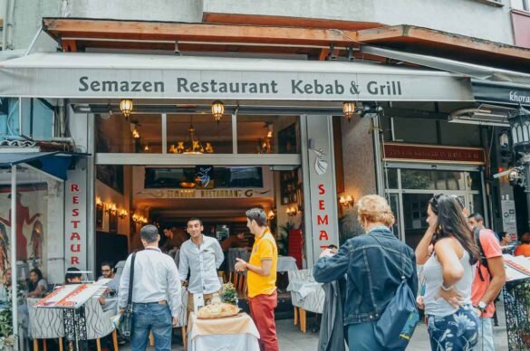 Fachada do restaurante Semazen Kebab & Grill com turistas e funcionários na entrada.