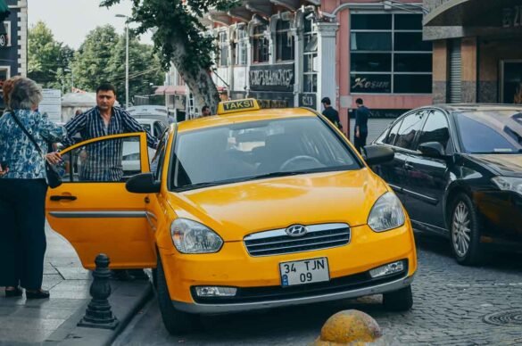 Táxi amarelo modelo Hyundai parado em uma rua movimentada de Istambul com passageiros embarcando.