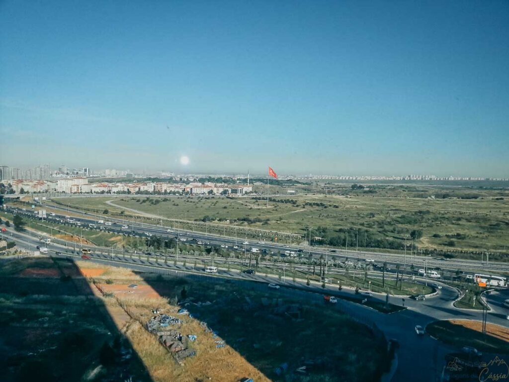 Vista panorâmica de uma rodovia, áreas verdes e a bandeira da Turquia ao fundo.