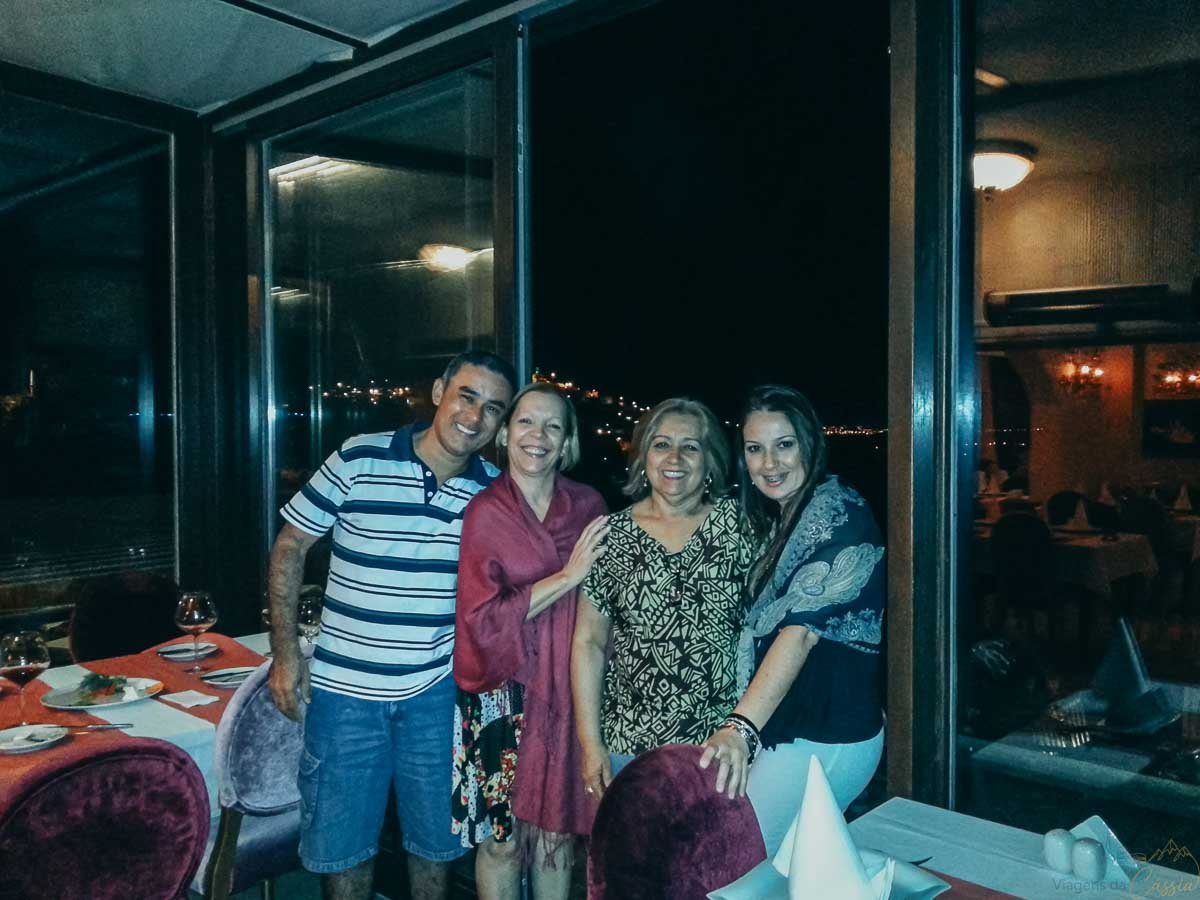 amigos-reunidos-restaurante-noite-turquia Quatro pessoas sorrindo juntas no interior de restaurante à noite.