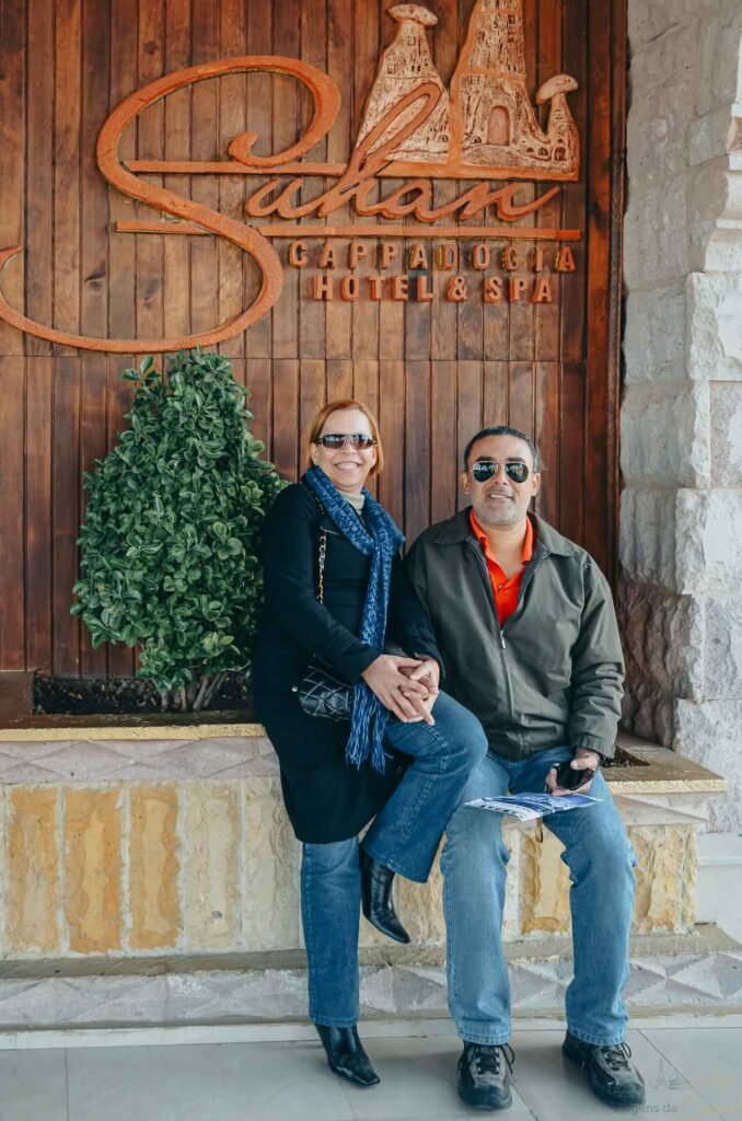 Casal sentado na entrada do Suhan Cappadocia Hotel & Spa posando para foto.