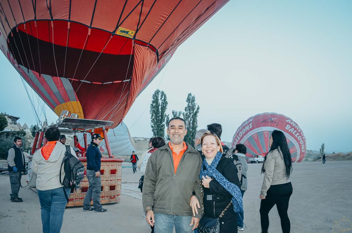 casal-sorrindo-antes-voo-balao Casal sorridente posando em frente à cesta de um balão de ar quente.