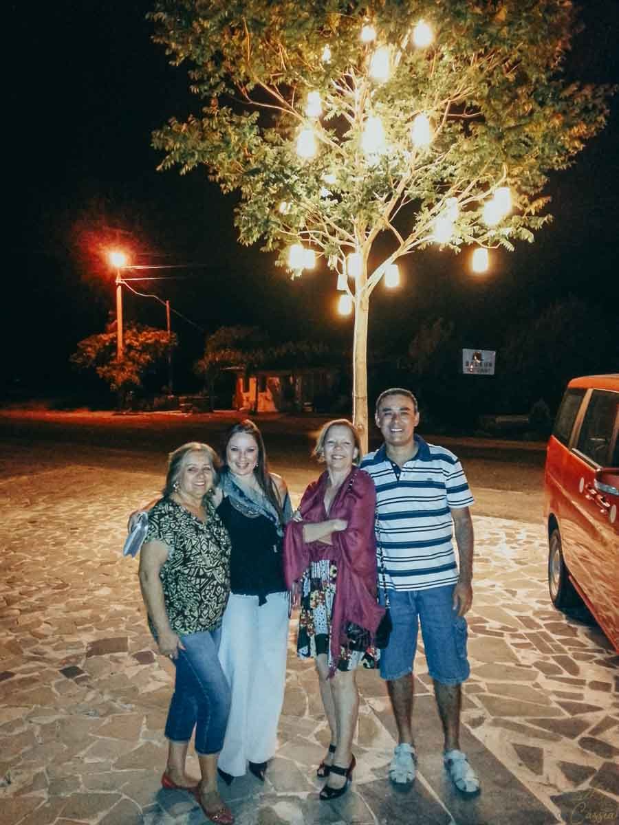 grupo-sob-arvore-iluminada-noite-turquia Quatro pessoas posando sob árvore iluminada por lanternas à noite.