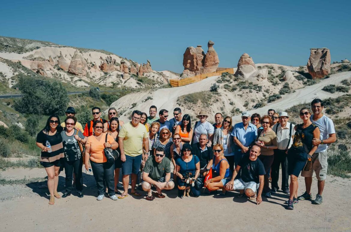 Grande grupo de turistas posando em frente à rocha do camelo.