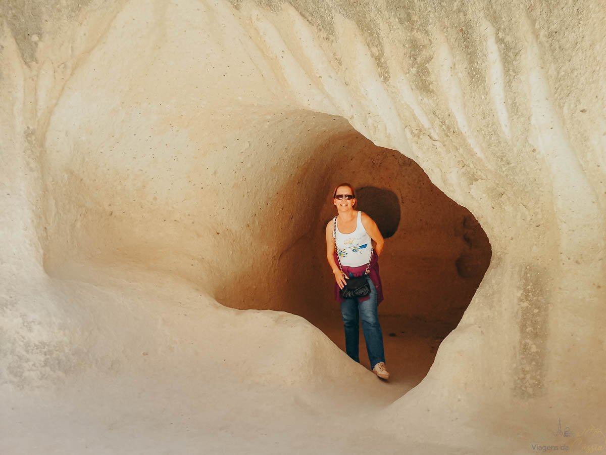 mulher-entrada-caverna-branca-tufo Mulher sorrindo na entrada de uma caverna de pedra vulcânica branca e lisa.