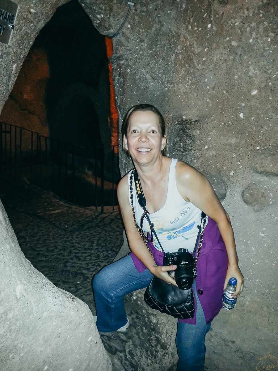 mulher-entrada-tunel-escuro-caverna Mulher sorrindo na entrada de um túnel escuro escavado na rocha.