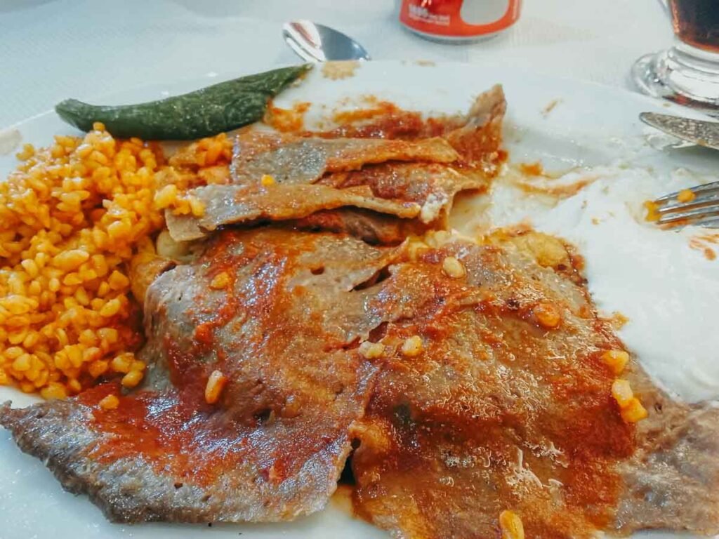 Prato com tiras de carne ao molho de tomate, bulgur picante e iogurte.