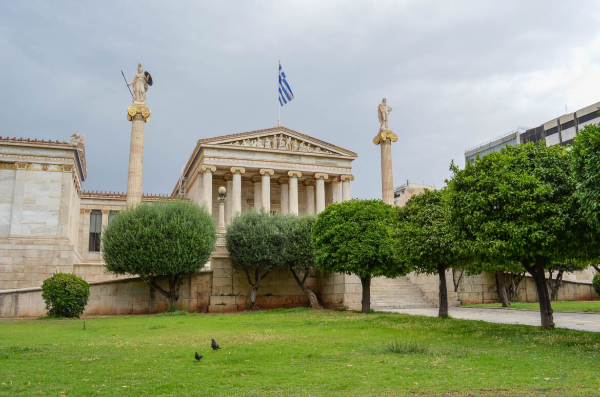 Fachada da Academia de Atenas com colunas jônicas e estátuas de Atena e Apolo.