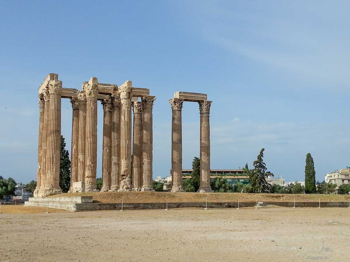 colunas-corintias-templo-zeus-olimpico-atenas Colunas coríntias preservadas do Templo de Zeus Olímpico em Atenas sob céu limpo.