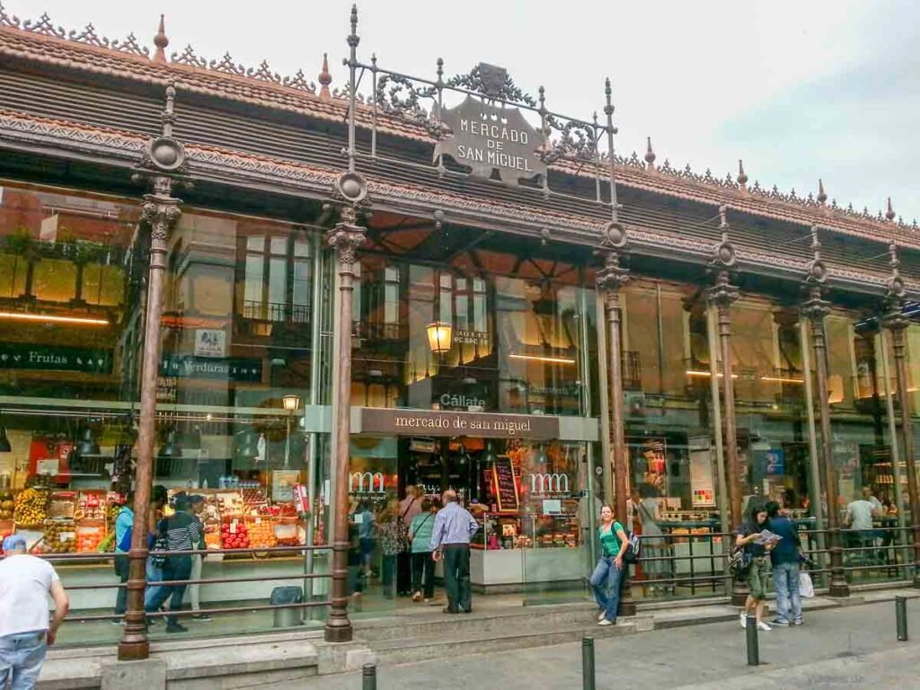 Mulher apoiada na vitrine de vidro e ferro do histórico Mercado de San Miguel em Madri.