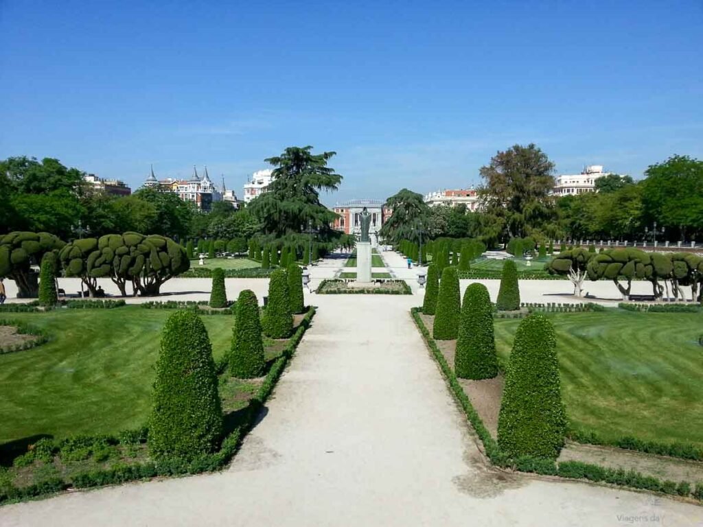 Jardim formal em estilo francês com arbustos topiados e caminho central no Parque do Retiro.