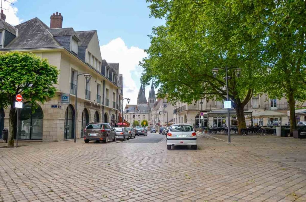 Rua pavimentada com paralelepípedos e vista para torres históricas ao fundo em Blois.