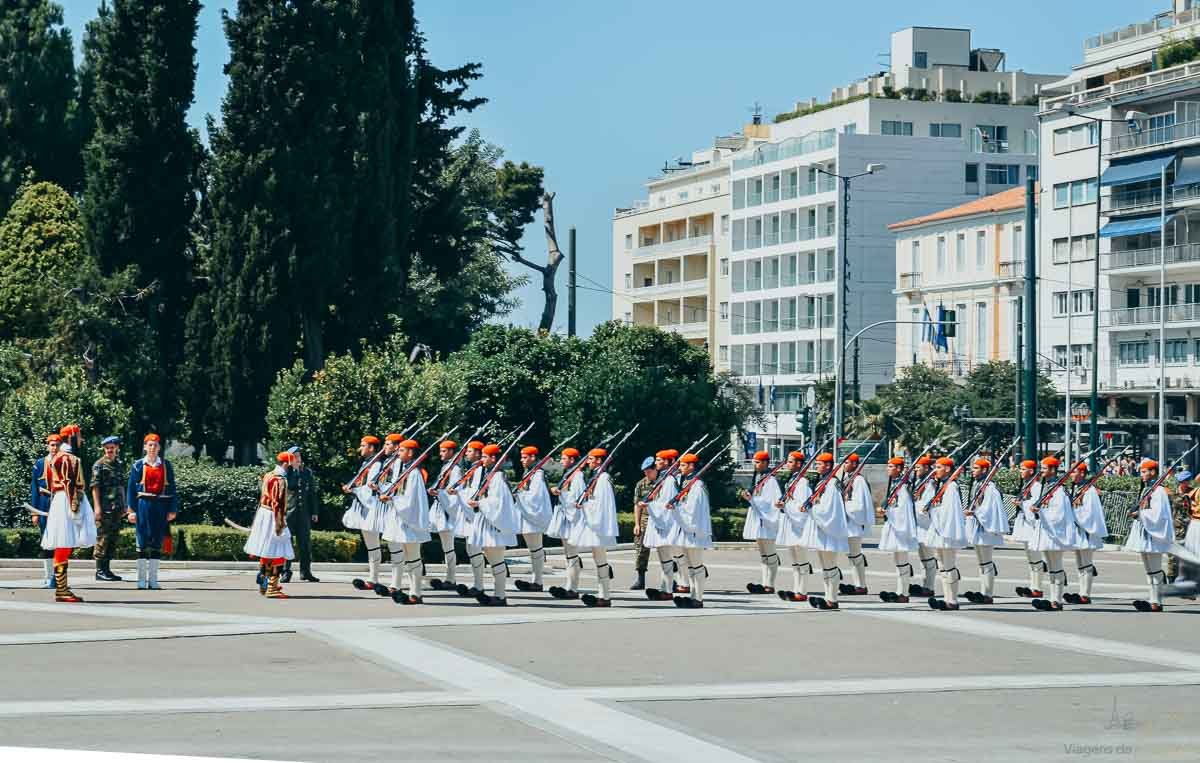 soldados-evzones-marcha-atenas-parlamento Fileira de guardas gregos Evzones marchando em trajes tradicionais brancos na praça em Atenas.