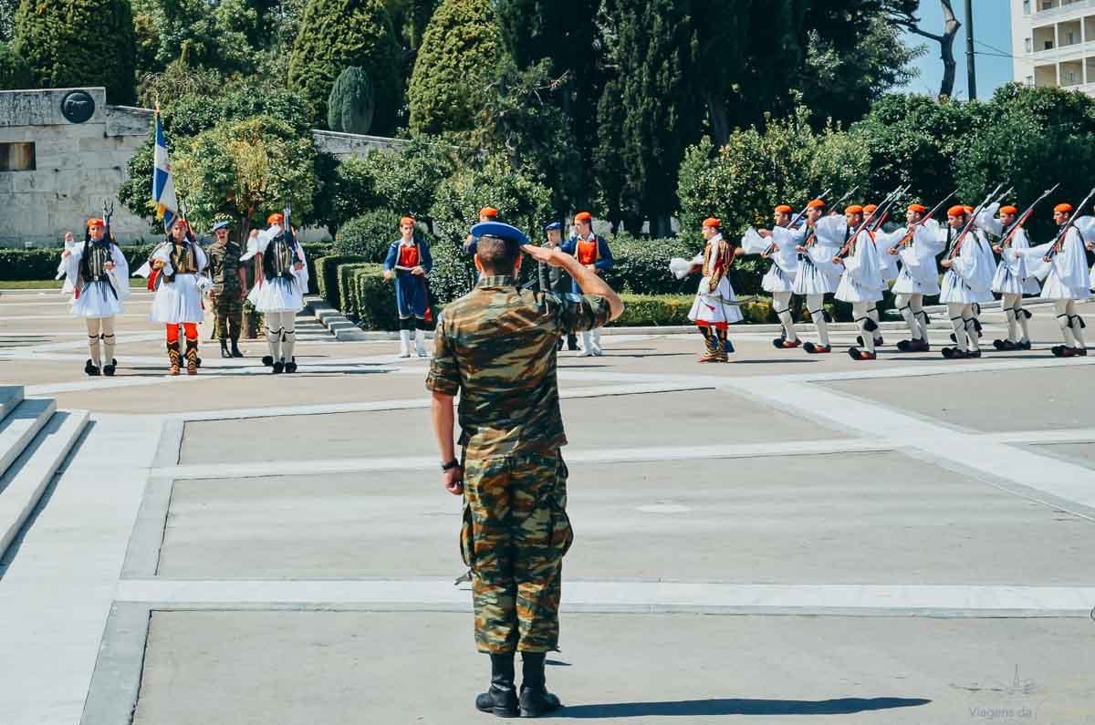 troca-da-guarda-evzones-atenas-grecia Soldado em farda militar prestando continência para pelotão de guardas Evzones em trajes tradicionais.