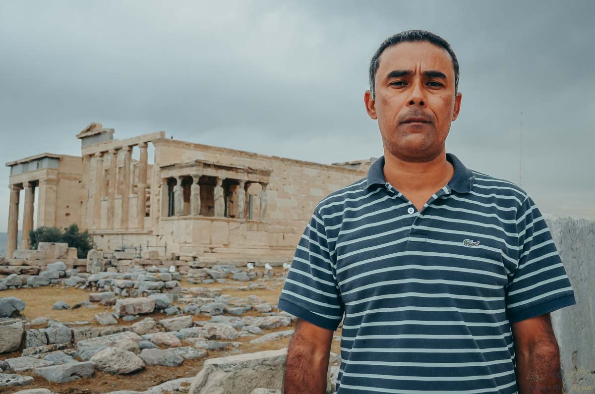 viajante-frente-erechtheion-acropole-atenas Homem posando em primeiro plano com o templo Erecteion e as Cariátides ao fundo na Acrópole.